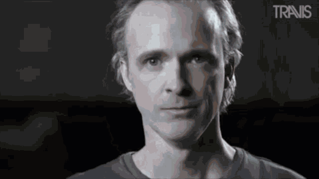 a close up of a man 's face with the word travis in the corner