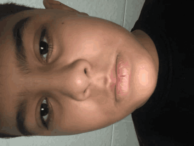 a close up of a person 's face with a black shirt