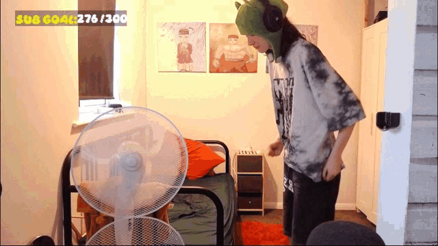 a person wearing a shrek hat is standing in front of a fan