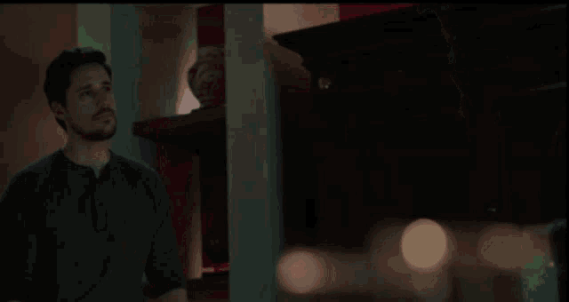 a woman in a dark room looking at a red item