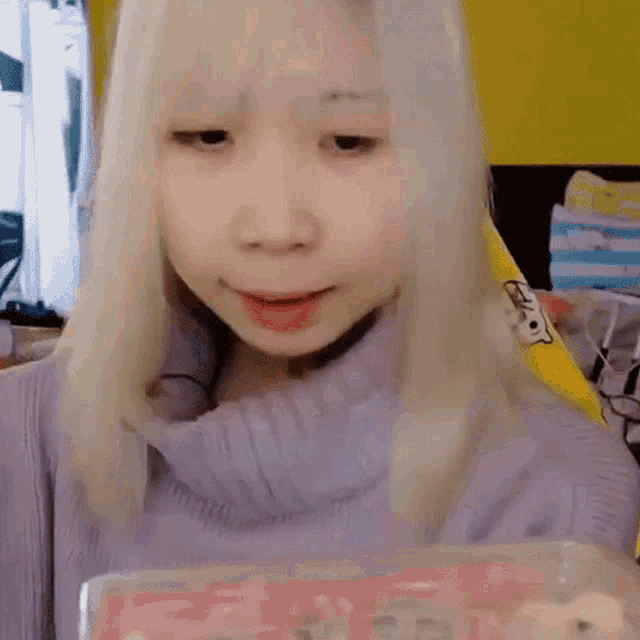 a girl with blonde hair says let 's get started in front of a yellow wall