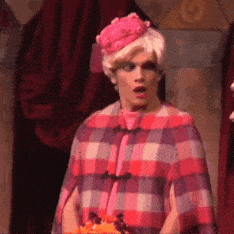 a man in a pink plaid coat and hat is standing on a stage .