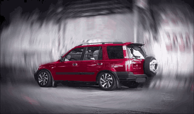 a red suv with a spare tire on the back is driving through a tunnel