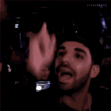 a man with a beard wearing a hat is waving his hand in the air