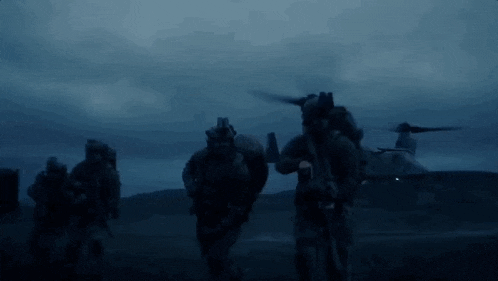 a group of soldiers are walking in front of a helicopter in the dark .