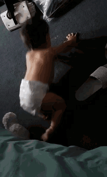 a baby in a diaper is crawling on the floor in a dark room .
