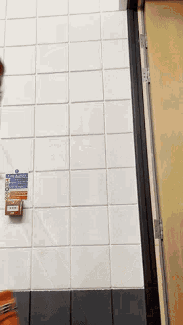 a white tiled wall with a sign that says fire alarm
