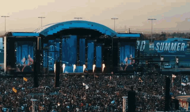 a large crowd is gathered at a concert with a sign that says summer