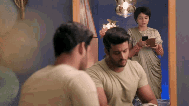 a man looking at his reflection in a mirror while a woman looks on