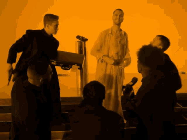 a group of men are standing in front of an orange wall