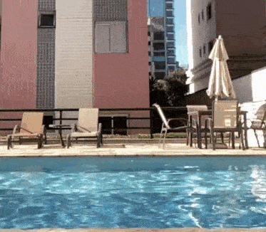 a swimming pool with chairs tables and umbrellas around it