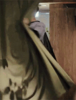 a person with long hair is standing in a room with a wooden wall behind them