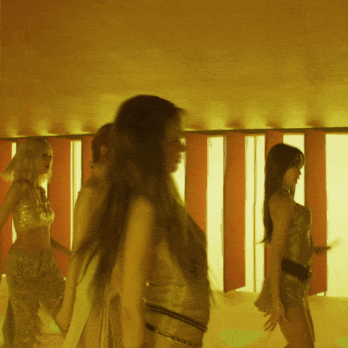 a group of women are dancing in a room with yellow lights