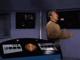 a man in a yellow sweater is standing in front of a control panel with his mouth open