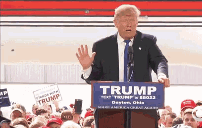 donald trump is giving a speech at a podium that says trump on it