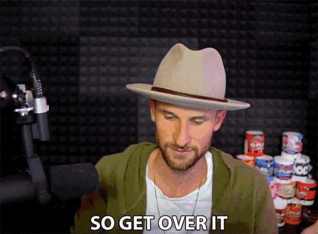 a man in a hat says " so get over it " in front of a microphone