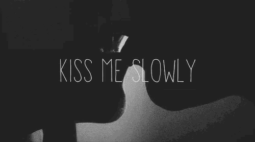 a black and white photo of a man and woman kissing with the words `` kiss me slowly '' written on the bottom .