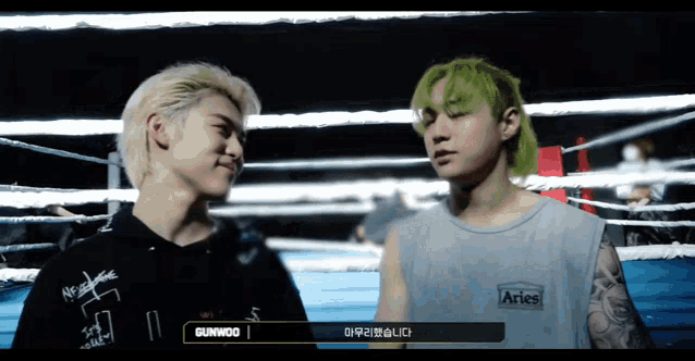 two men in a boxing ring with one wearing a shirt that says aries on it
