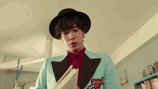 a man wearing a blue suit and a black hat is holding a book