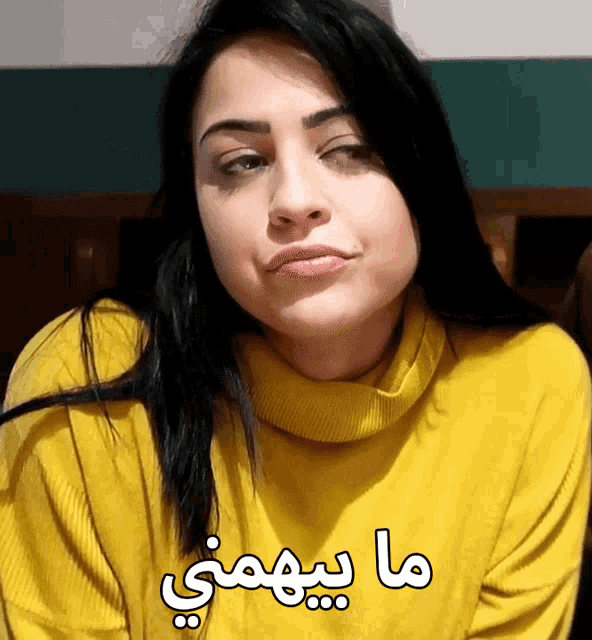 a woman wearing a yellow sweater has arabic writing on her sweater