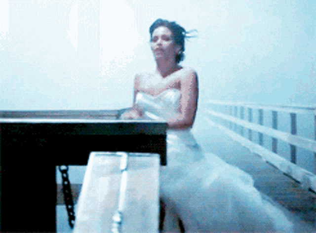 a woman in a wedding dress stands on a bridge