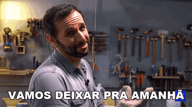 a man stands in front of a wall of tools with the words vamos deixar pra amanha above him