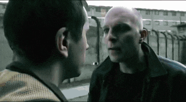two men are standing next to each other and talking .
