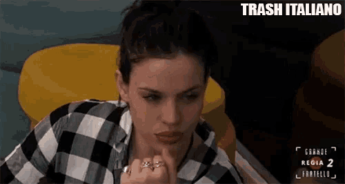 a woman in a plaid shirt is sitting on a yellow chair and making a funny face .