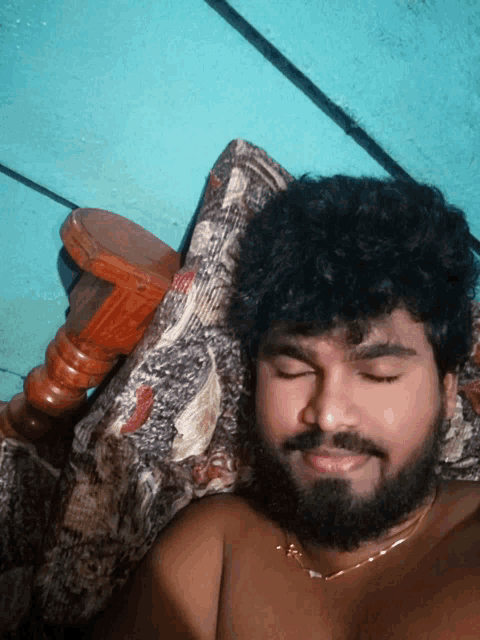a man with a beard is sleeping on a bed with his eyes closed