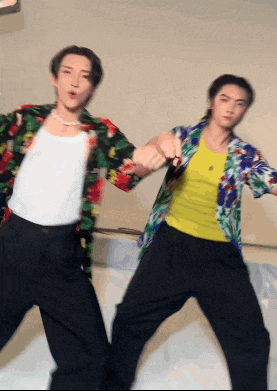 a man in a yellow tank top is dancing with another man in a colorful shirt