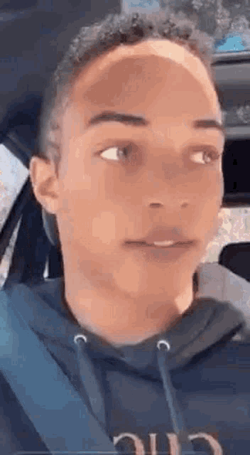 a young man is sitting in the driver 's seat of a car looking at the camera .