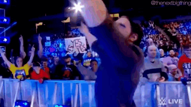 a wrestler is holding a sign that says `` yes sir '' in front of a crowd of people .