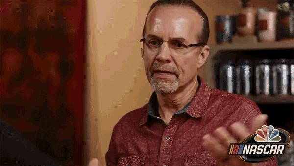 a man wearing glasses and a red shirt with nascar written on it