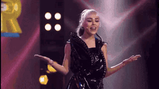 a woman in a black dress is dancing on stage