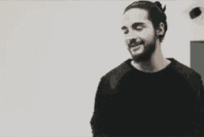 a man with a beard is smiling and wearing a black sweater