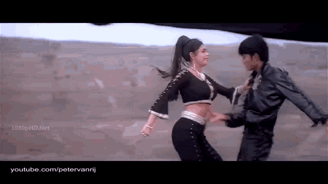 a man and a woman are dancing in a field . the woman is wearing a black crop top .