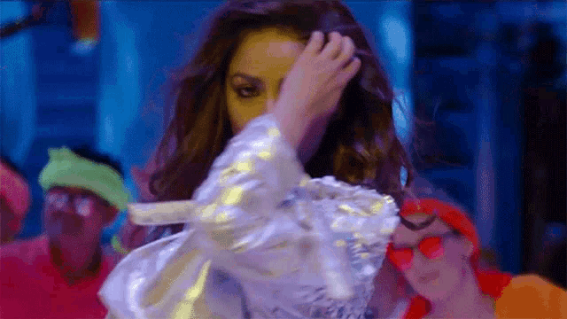 a woman in a silver jacket is dancing in a club .