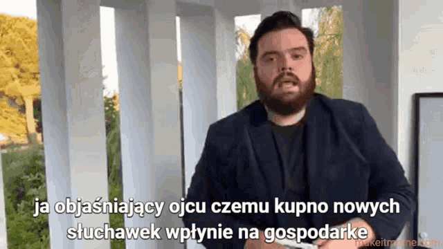 a man with a beard is standing in front of a sign that says ja objawiajacy