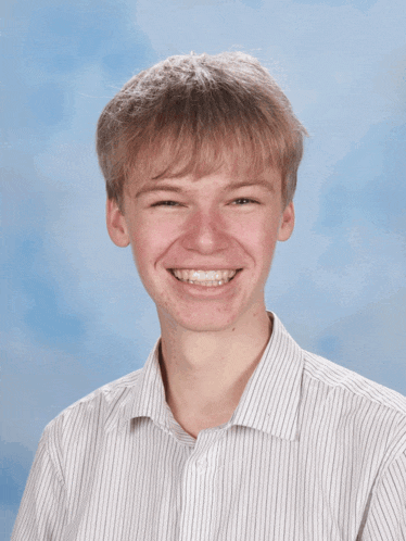 a young man wearing a white striped shirt smiles for the camera