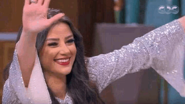 a woman in a silver sequined dress is waving her hand .