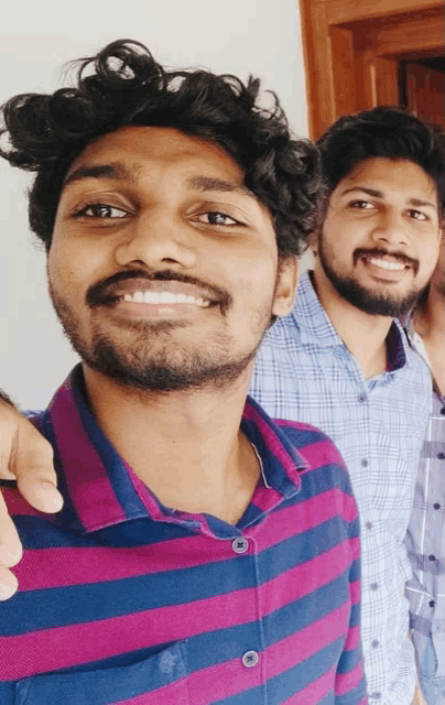 two men are posing for a picture and one of them is wearing a striped shirt
