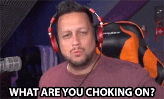a man wearing headphones is sitting in front of a microphone and asking what are you choking on .