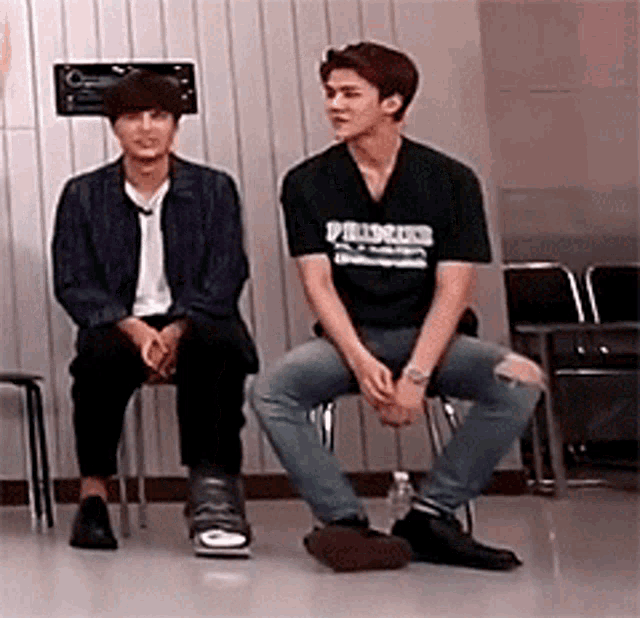 two men are sitting in chairs in a room .