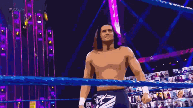 a man with long hair is standing in front of a sign that says ' 205 live '
