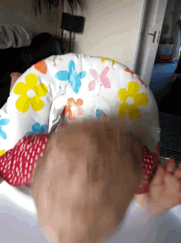 a baby is sitting in a high chair with flowers on the cushion