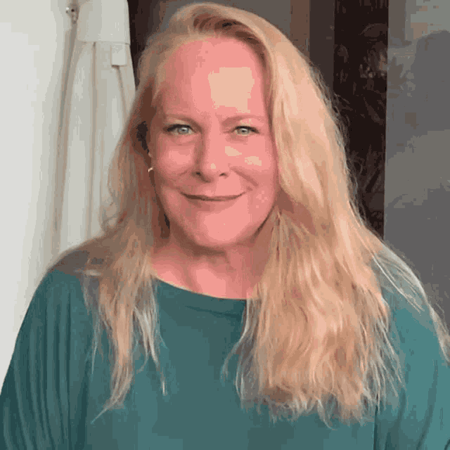 a woman with blonde hair and green eyes is wearing a green shirt
