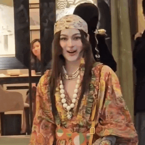 a woman wearing a floral dress and a headband is standing in front of a store .