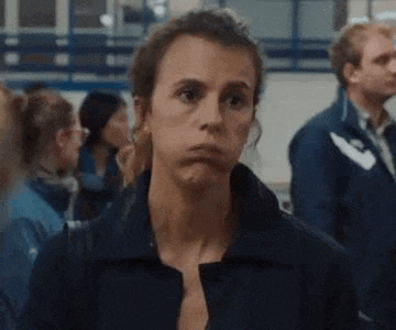 a woman is making a funny face while standing in front of a crowd of people .