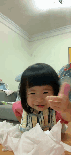 a little girl is playing with a pile of toilet paper on the floor