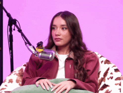 a woman is sitting in a chair with a microphone in front of her
